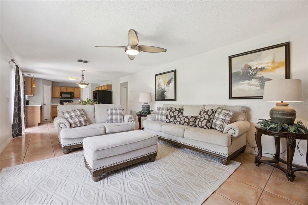 A living room features light-colored sofas, a matching ottoman, and tile flooring — 670 BROWN BEAR COURT, ST CLOUD, FL