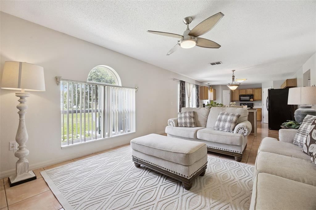 A living room with a beige sofa, ottoman, area rug, and ceiling fan — 670 BROWN BEAR COURT, ST CLOUD, FL