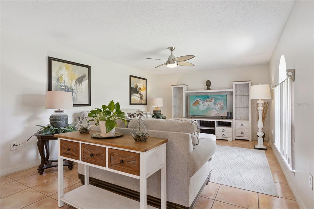 A living room features a sofa, console table, entertainment center, and tile flooring — 670 BROWN BEAR COURT, ST CLOUD, FL