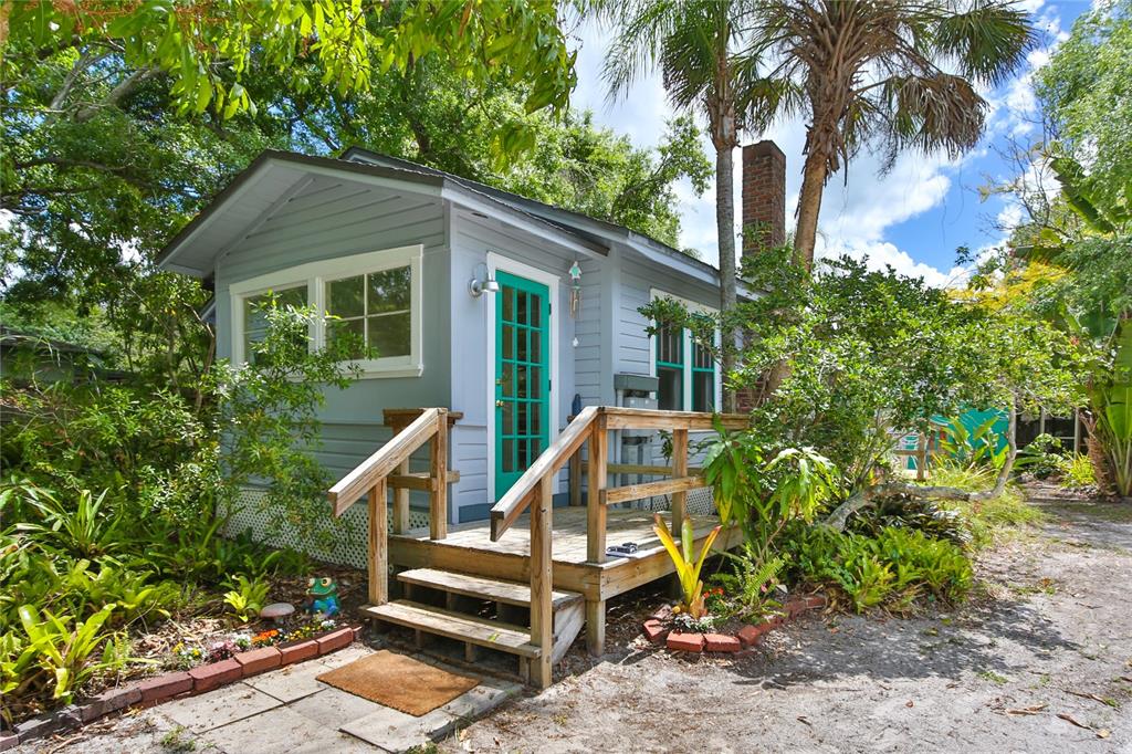 A small, light blue cottage with a teal front door and a wooden porch — 708 42ND STREET, SARASOTA, FL