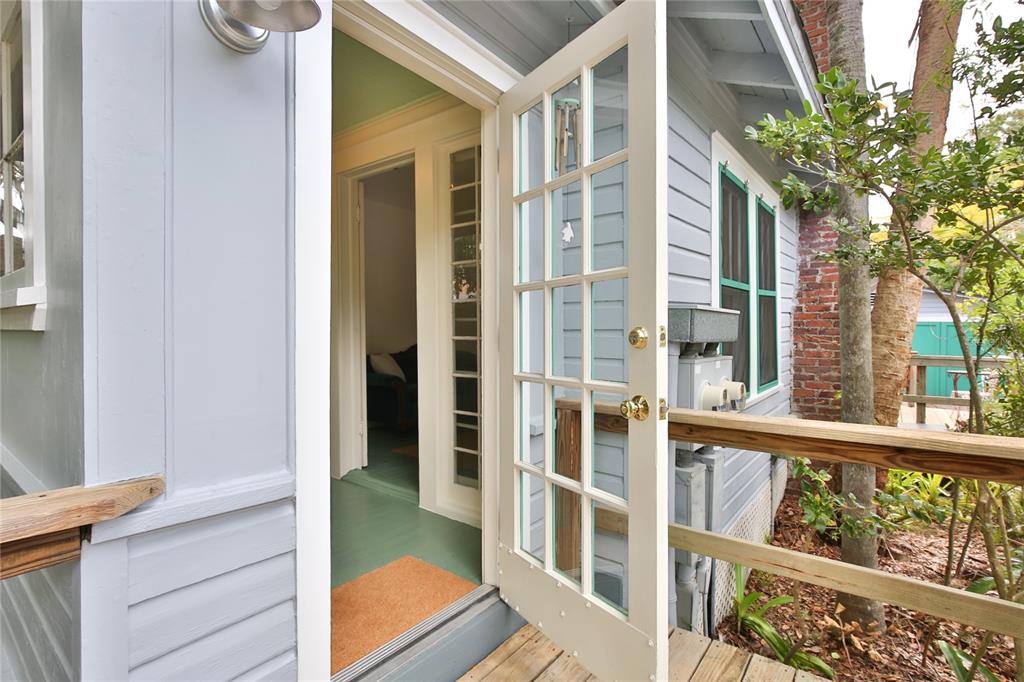 An open glass-paned door leads from a wooden deck into a house with light-blue siding — 708 42ND STREET, SARASOTA, FL