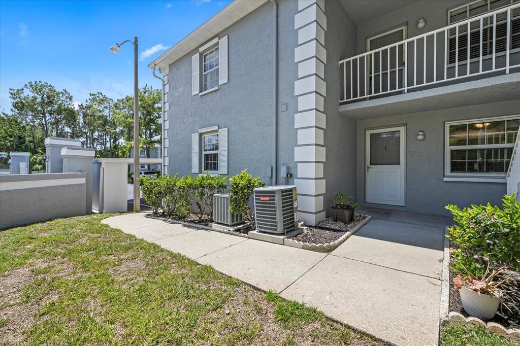 A two-story gray building with white trim, a concrete walkway, and two outdoor AC units — 12141 SPARTAN WAY UNIT 102, HUDSON, FL