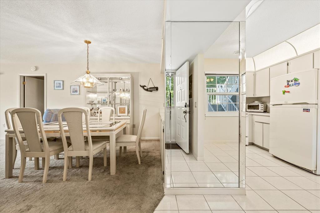 A dining area with carpeted floors and a kitchen with white appliances and tiled floors — 12141 SPARTAN WAY UNIT 102, HUDSON, FL