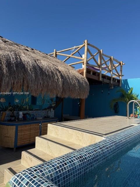 A swimming pool with tiled steps sits beside a tiki hut and a wooden deck — 1405 25 th street # 1405, MX, MX