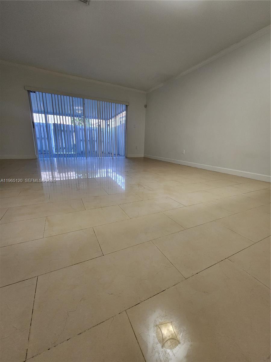 An empty room features light-colored tile flooring and a large sliding glass door — 6485 SW 129th Ave, Miami FL 33183, MIAMI, FL