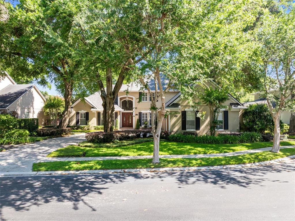 A two-story suburban house with a tan exterior, dark shutters, and a large front yard — 873 CRANES COURT, MAITLAND, FL