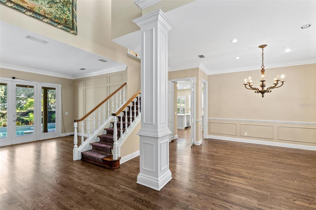 A foyer with hardwood floors, a white column, and a staircase leading to an upper level — 873 CRANES COURT, MAITLAND, FL