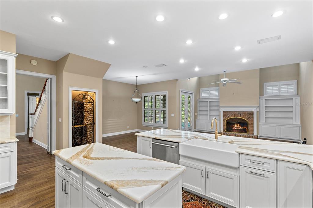 A kitchen with white cabinetry, a large island with marble countertops, and a brick fireplace — 873 CRANES COURT, MAITLAND, FL