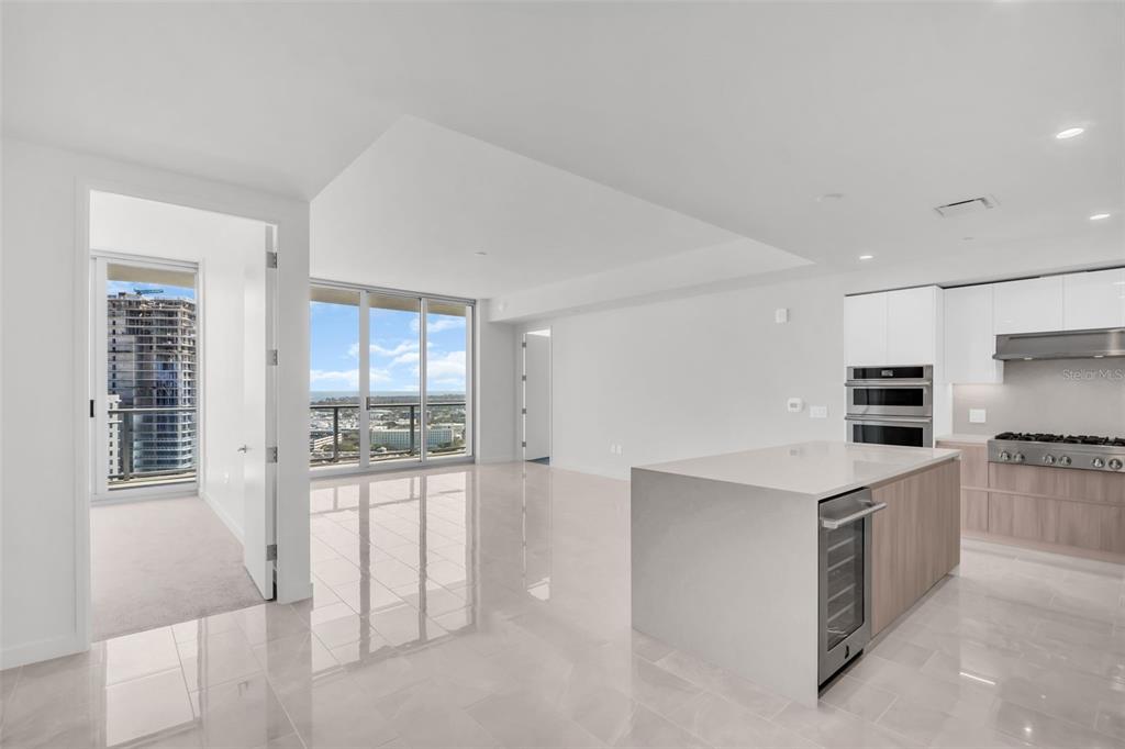 A modern kitchen with a large island and white cabinets opens to a bright living area — 400 CENTRAL AVENUE UNIT 2205, ST PETERSBURG, FL