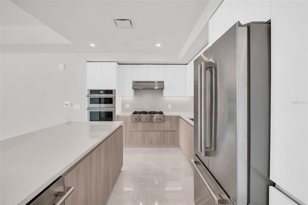 A modern kitchen features white upper cabinets, light wood lower cabinets, and stainless steel appliances — 400 CENTRAL AVENUE UNIT 2205, ST PETERSBURG, FL