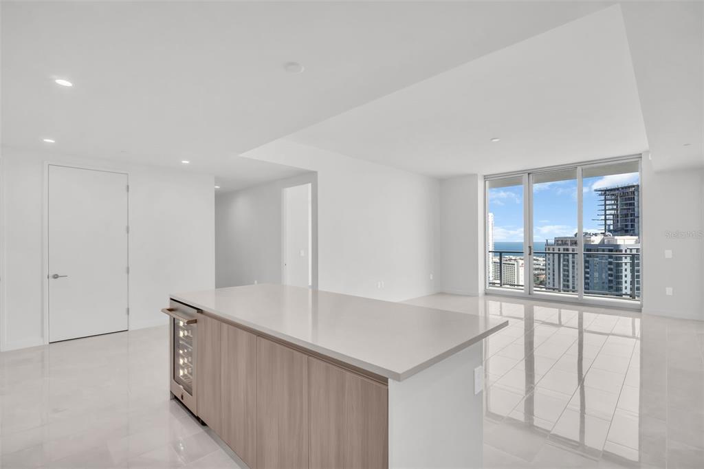 A modern kitchen island with a wine cooler sits in a bright, open-plan living space — 400 CENTRAL AVENUE UNIT 2205, ST PETERSBURG, FL