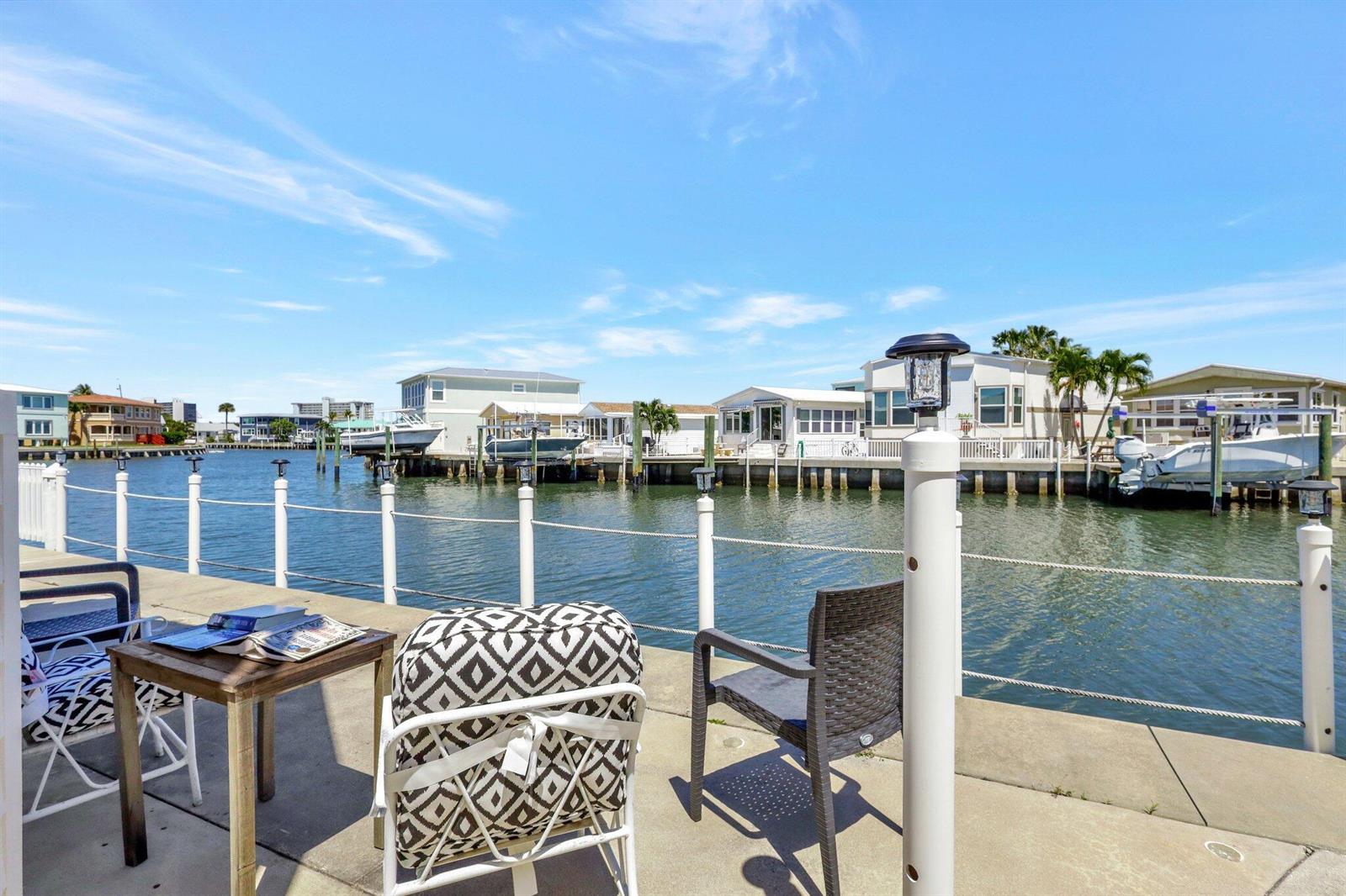 A concrete patio overlooks a canal with docked boats and waterfront homes under a blue sky — 10701 S Ocean Drive # 651, Jensen Beach FL 34957, JENSEN BEACH, FL