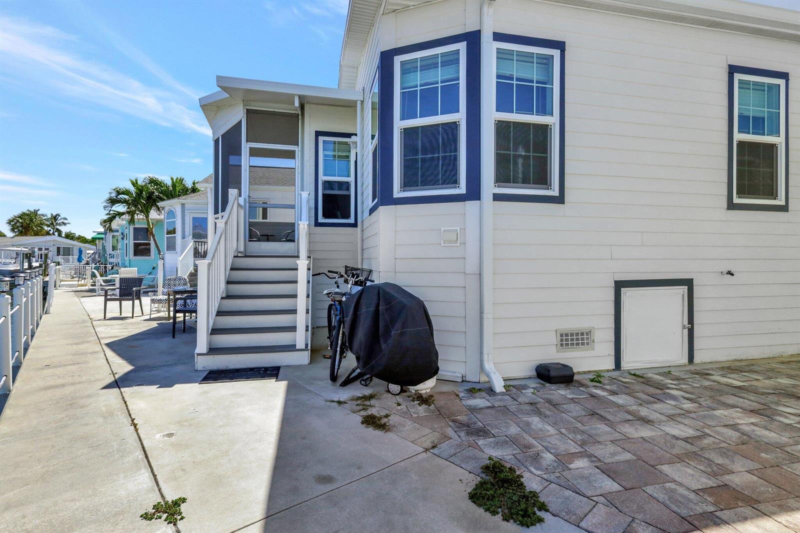 The exterior of a white house features a screened porch, stairs, and a paved patio — 10701 S Ocean Drive # 651, Jensen Beach FL 34957, JENSEN BEACH, FL