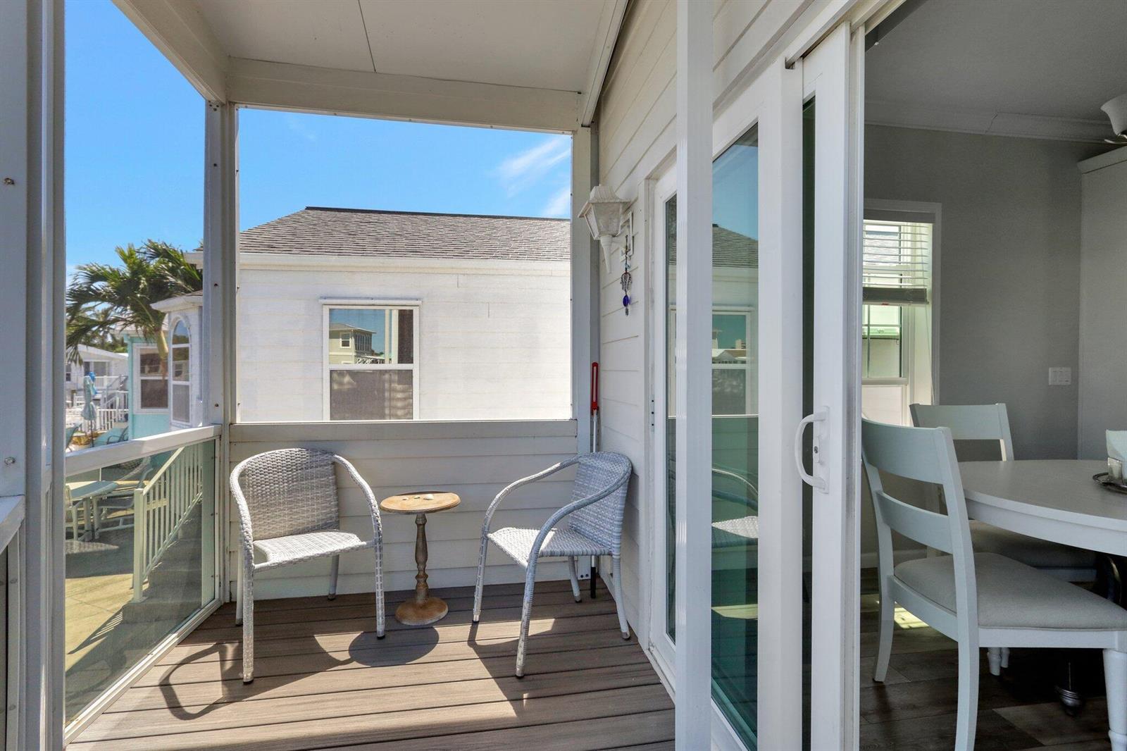 A screened-in porch with two wicker chairs and a small table overlooks a neighboring house — 10701 S Ocean Drive # 651, Jensen Beach FL 34957, JENSEN BEACH, FL