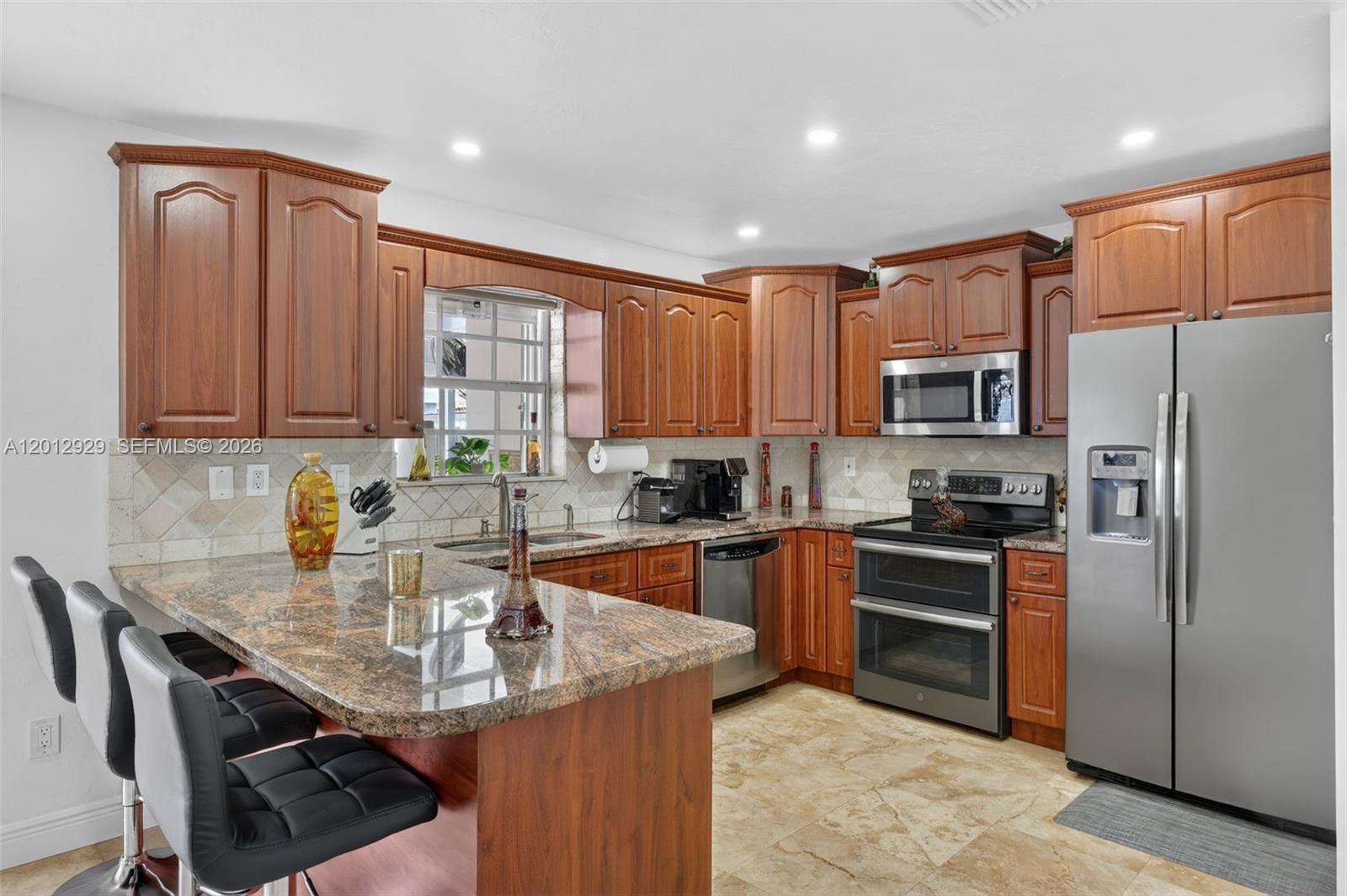 A kitchen features wood cabinets, granite countertops, stainless steel appliances, and a breakfast bar — 14661 SW 168th Ter, Miami FL 33177, MIAMI, FL