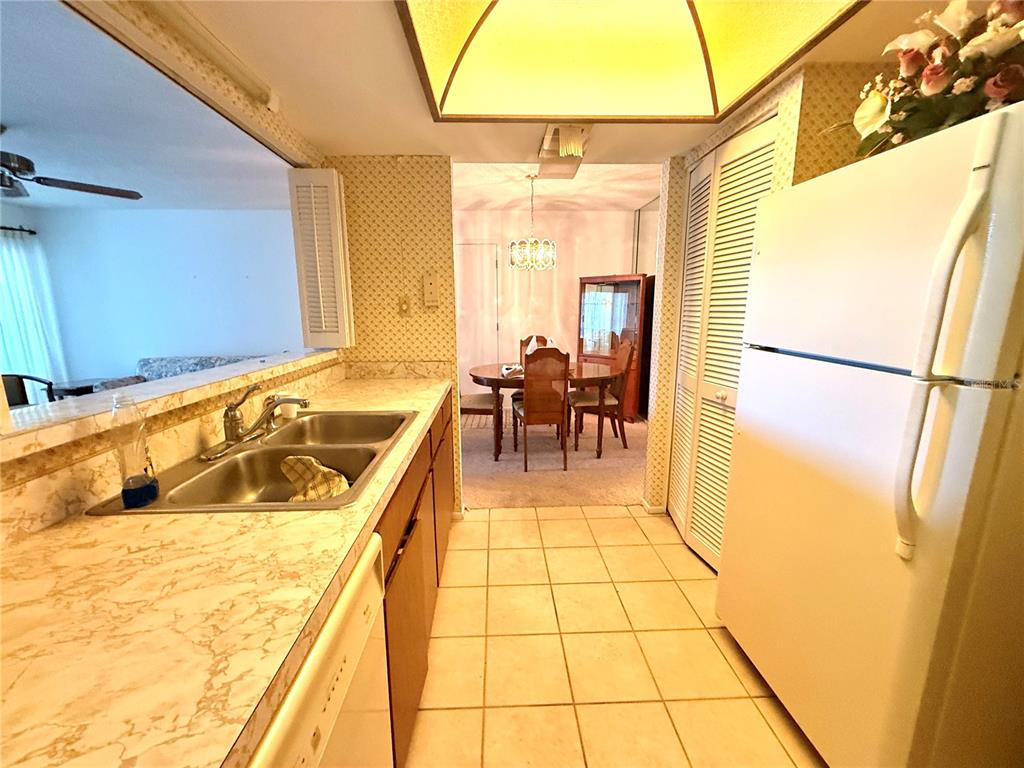 A kitchen with marble-look countertops and a double sink overlooks a dining room area — 8111 BUGLE COURT UNIT 2, PORT RICHEY, FL
