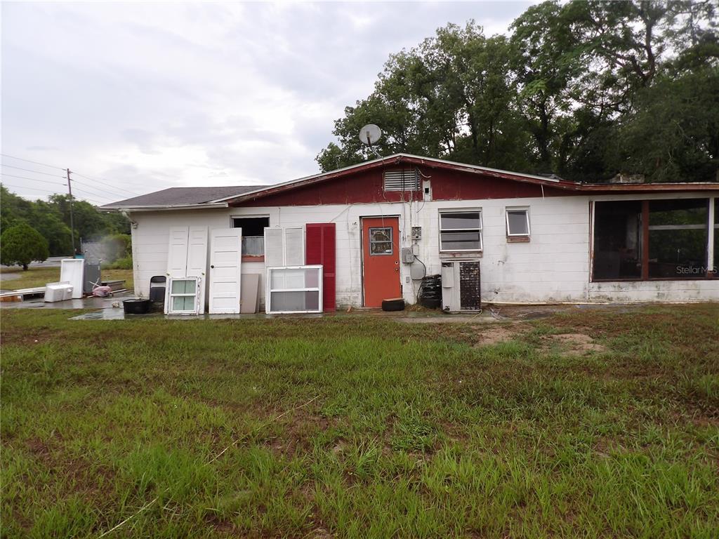 The exterior of a single-story house with a white block wall and red trim — 9706 MOON LAKE RD, NEW PORT RICHEY, FL
