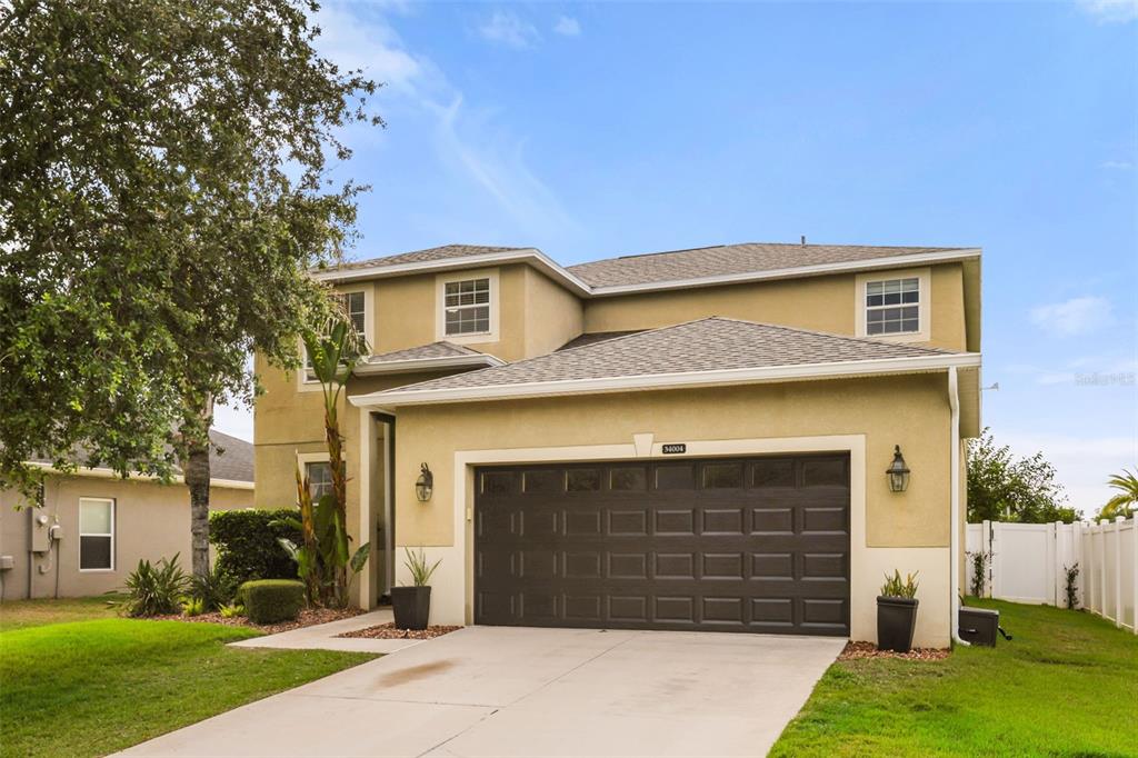 A two-story suburban house with a tan stucco exterior and a two-car garage — 34004 ALAMEDA DRIVE, SORRENTO, FL