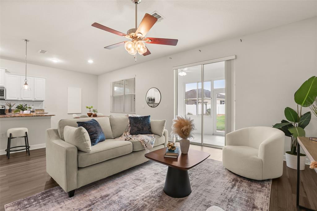 A living room features a beige sofa, a white armchair, and a ceiling fan — 34004 ALAMEDA DRIVE, SORRENTO, FL