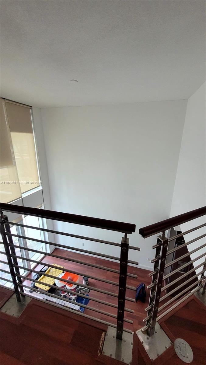 A high-ceilinged room with a wooden staircase, metal railing, and large windows — 41 SE 5th St # 709, Miami FL 33131, MIAMI, FL