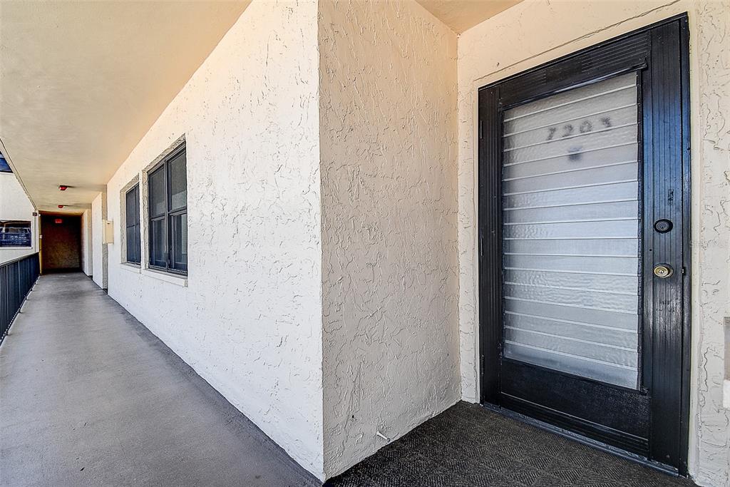 An exterior view of a building hallway with a black door labeled 7203 — 12300 VONN ROAD UNIT 7203, LARGO, FL