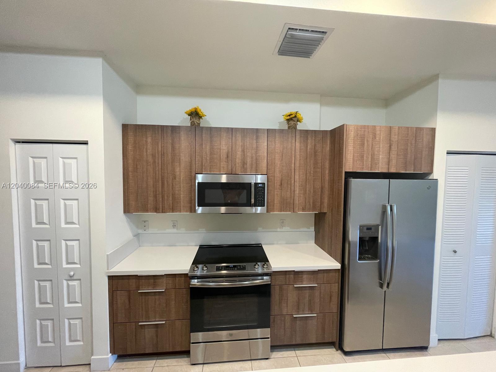 A kitchen features wood-grain cabinets, stainless steel appliances, and white countertops — 8025 NW 104th Ave # 31, Doral FL 33178, DORAL, FL