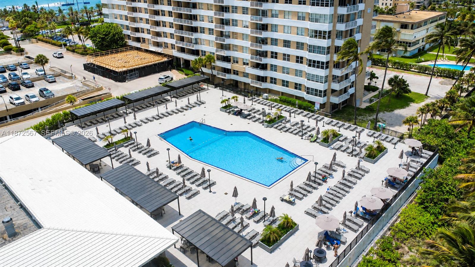 An aerial view shows a large swimming pool surrounded by lounge chairs and covered patios — 1950 S Ocean Dr # 11D, Hallandale Beach FL 33009, HALLANDALE BEACH, FL