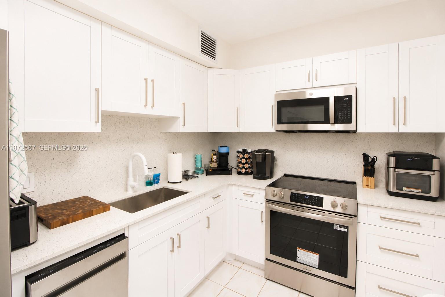 A kitchen features white cabinets, stainless steel appliances, and light-colored countertops — 1950 S Ocean Dr # 11D, Hallandale Beach FL 33009, HALLANDALE BEACH, FL