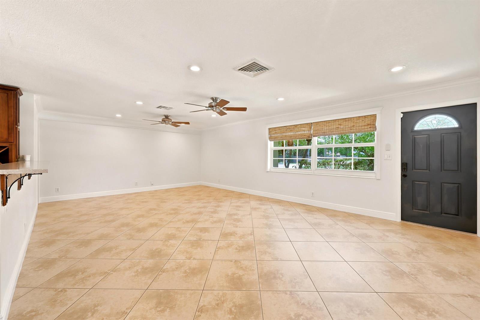 A spacious room features beige tile flooring, white walls, two ceiling fans, and a dark door — 1222 SW 5th Street, Boca Raton FL 33486, BOCA RATON, FL