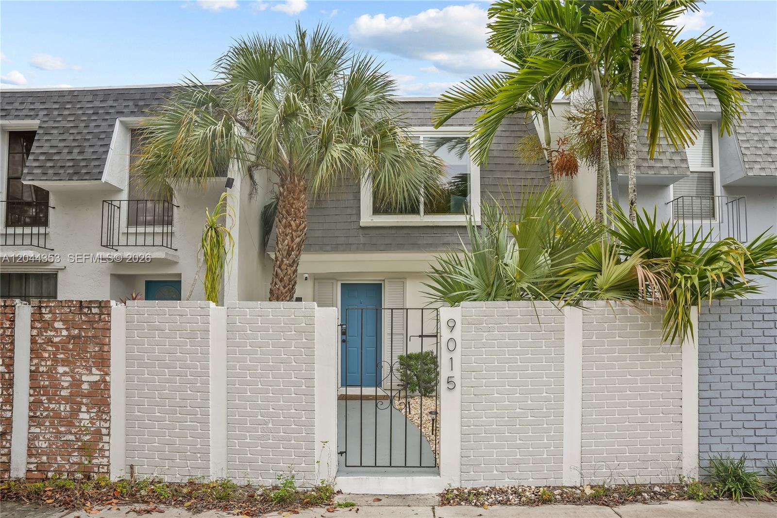 A two-story townhouse features a blue front door behind a white brick privacy wall — 9015 SW 96 Ave # 1, Miami FL 33176, MIAMI, FL