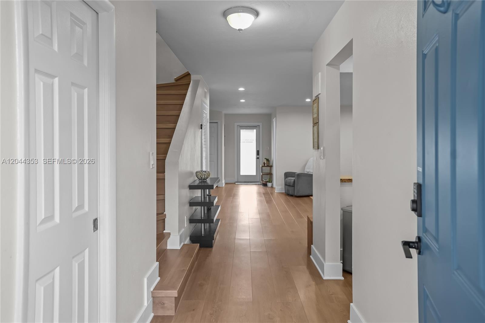 A hallway features light wood flooring, a staircase with wooden steps, and a blue door — 9015 SW 96 Ave # 1, Miami FL 33176, MIAMI, FL