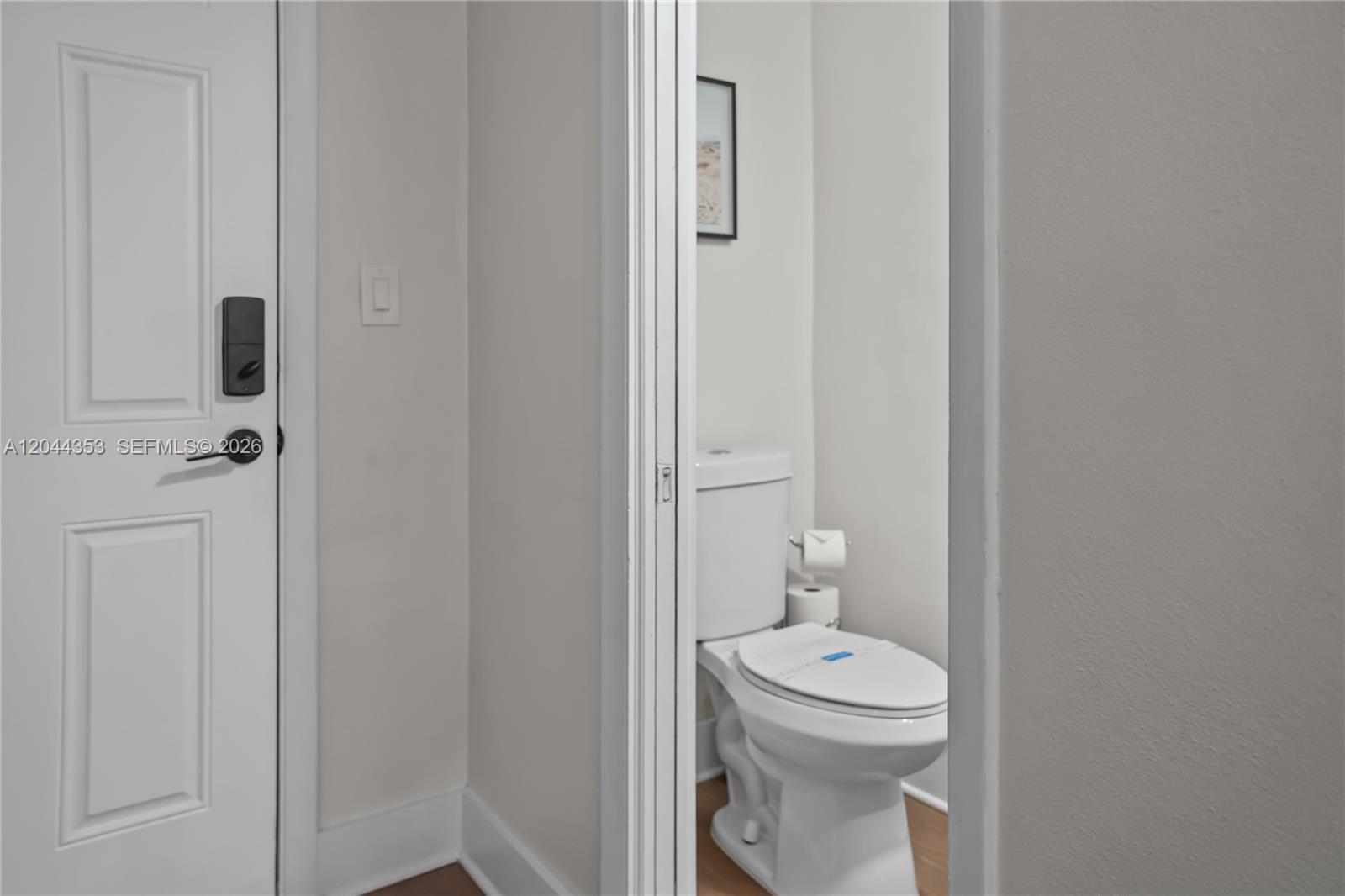A white door with a smart lock stands next to a small bathroom with a toilet — 9015 SW 96 Ave # 1, Miami FL 33176, MIAMI, FL