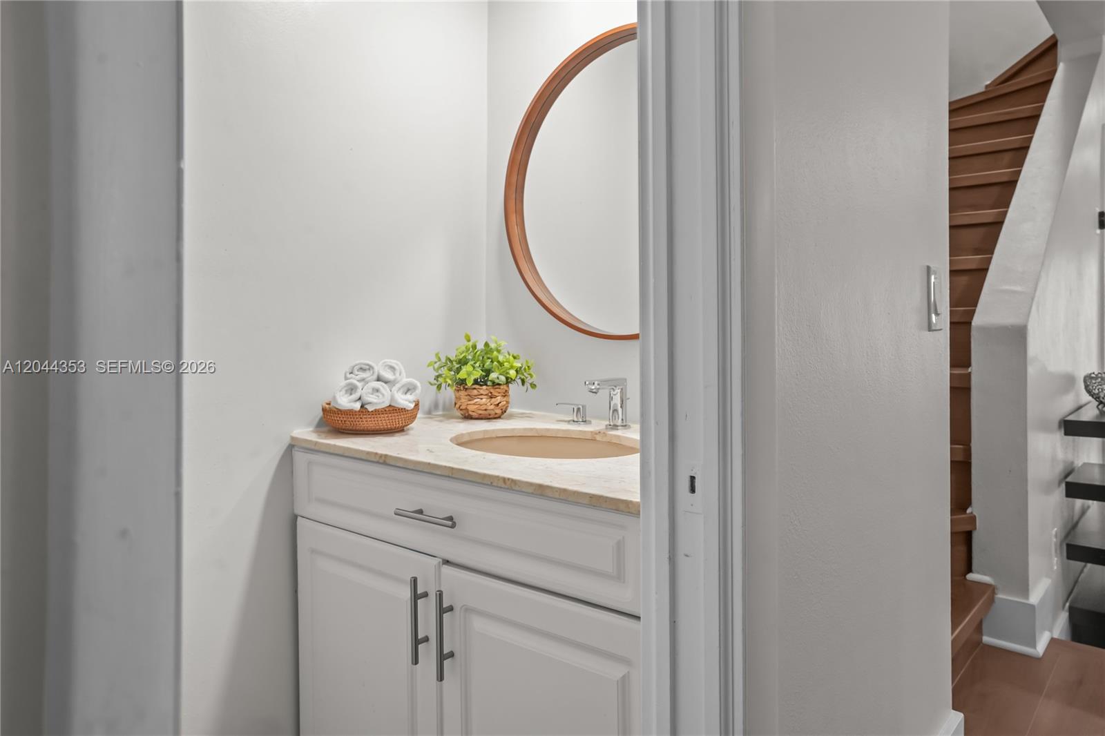 A small bathroom features a white vanity, a round mirror, and a staircase nearby — 9015 SW 96 Ave # 1, Miami FL 33176, MIAMI, FL