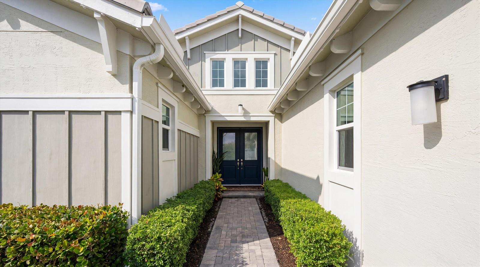 A brick walkway leads to the dark blue double front doors of a light-colored house — 5919 Jasmine Lane, Westlake FL 33470, WESTLAKE, FL