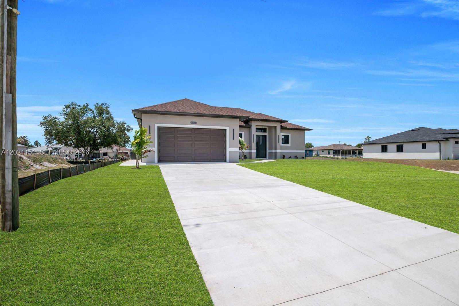 A single-story house with a brown garage door and a concrete driveway under a blue sky — 3115 2nd ST SW, Lehigh Acres FL 33976, LEHIGH ACRES, FL