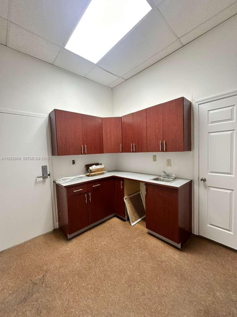 This room features dark wood cabinetry, a small sink, and a drop ceiling — 5911 NW 173rd Dr, Hialeah FL 33015, HIALEAH, FL