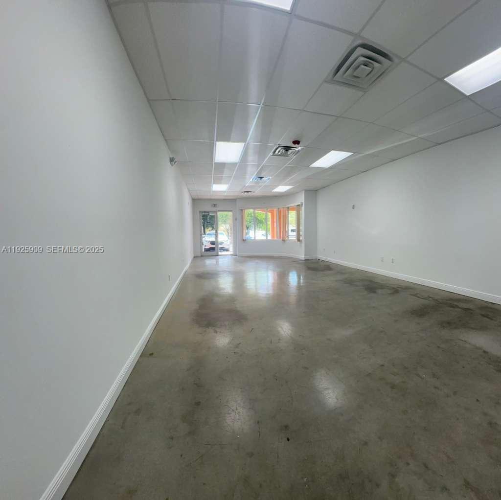 An empty commercial space features white walls, a drop ceiling with recessed lighting, and concrete floors — 5911 NW 173rd Dr, Hialeah FL 33015, HIALEAH, FL