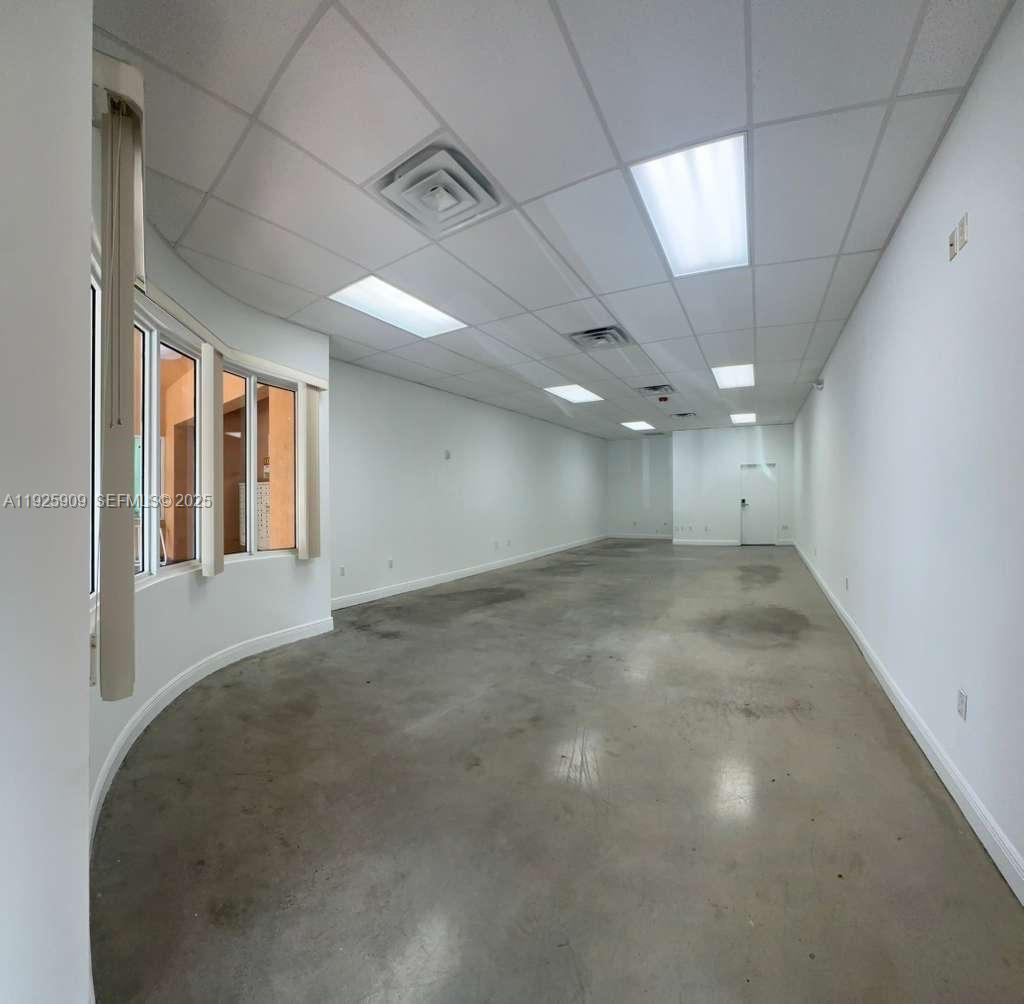 An empty commercial office space features a curved wall, concrete floors, and drop ceiling tiles — 5911 NW 173rd Dr, Hialeah FL 33015, HIALEAH, FL