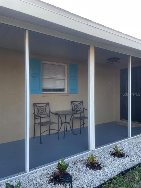 A screened-in porch features a small table, two chairs, and a window with blue shutters — 1580 SOUTHLAND ROAD, VENICE, FL