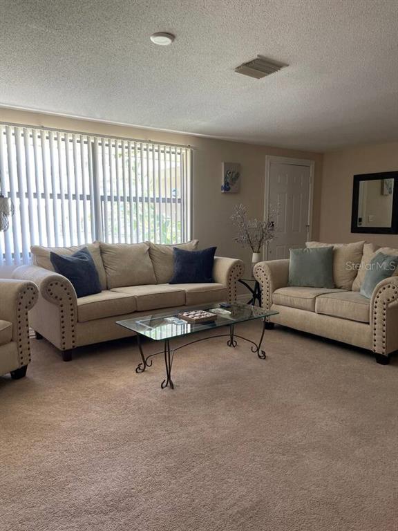 A living room features beige sofas, a glass coffee table, and vertical window blinds — 1580 SOUTHLAND ROAD, VENICE, FL