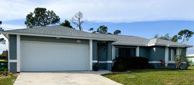 A single-story house with a two-car garage, gray siding, and a light-colored shingle roof — 22497 GLEN AVENUE, PUNTA GORDA, FL