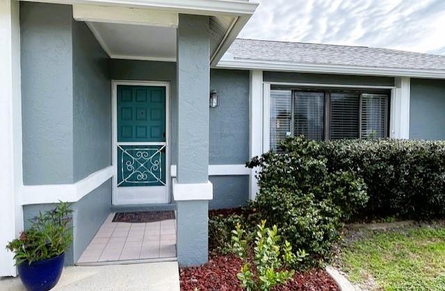 The exterior of a house features a teal front door, a covered porch, and landscaping — 22497 GLEN AVENUE, PUNTA GORDA, FL