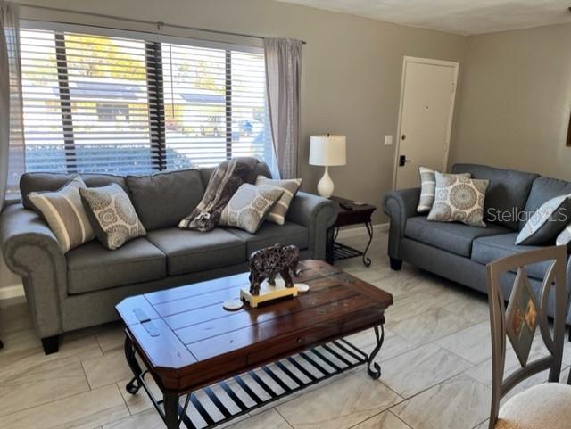 A living room features two gray sofas, a wooden coffee table, and tile flooring — 22497 GLEN AVENUE, PUNTA GORDA, FL