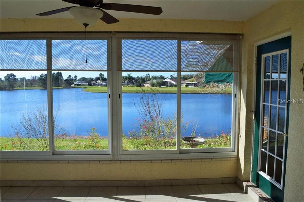 A sunroom with tile floors and large windows overlooking a lake and neighborhood houses — 29530 WAGGLE DRIVE, SAN ANTONIO, FL
