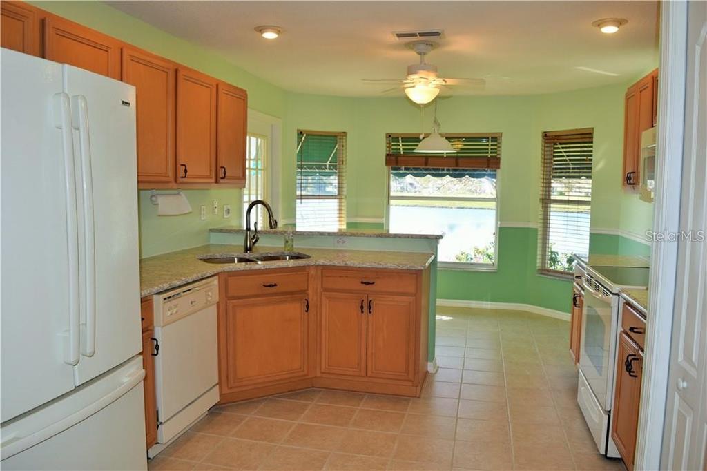 A kitchen with light wood cabinets, granite countertops, white appliances, and a view of water — 29530 WAGGLE DRIVE, SAN ANTONIO, FL