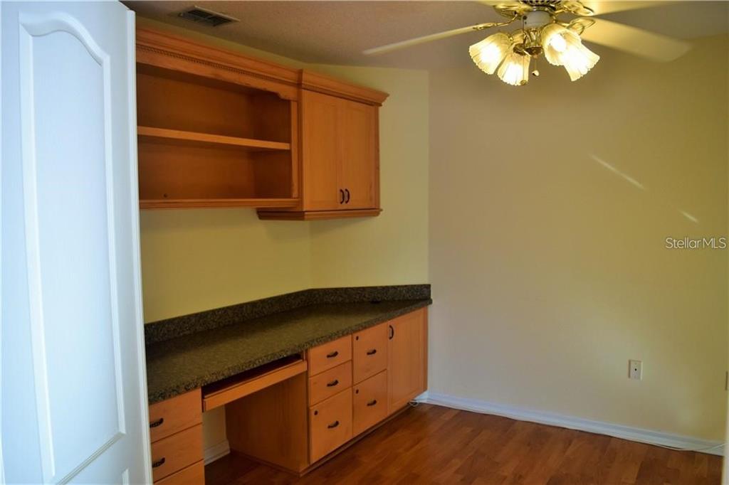 A home office features wood cabinetry, a dark countertop, and a ceiling fan — 29530 WAGGLE DRIVE, SAN ANTONIO, FL