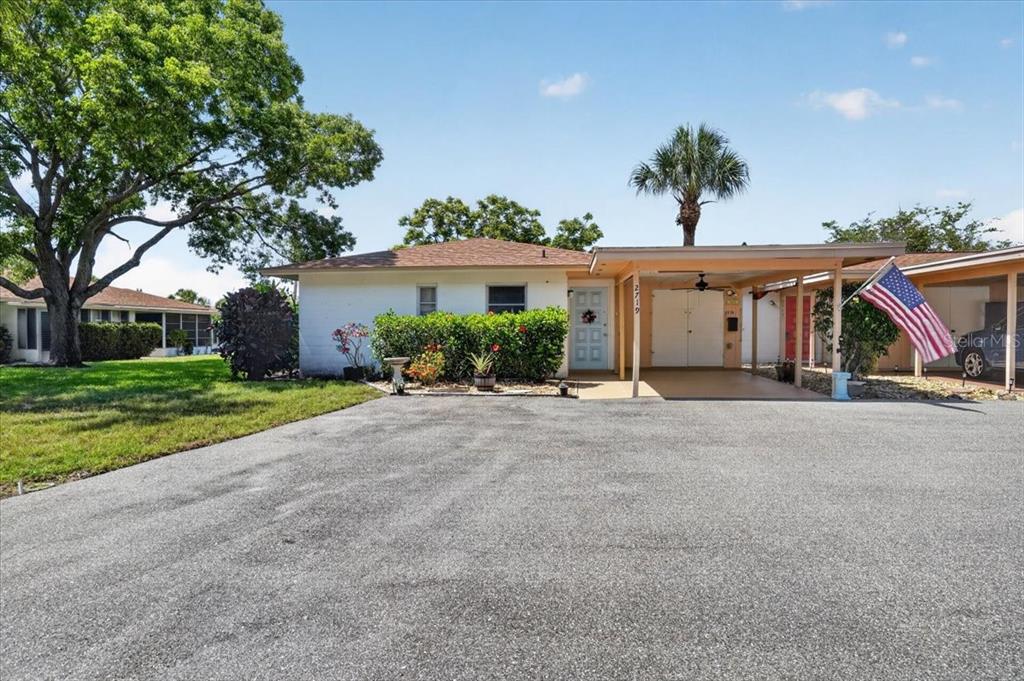 A single-story house with a white exterior, a carport, and a large paved driveway — 2719 51ST AVENUE W, BRADENTON, FL
