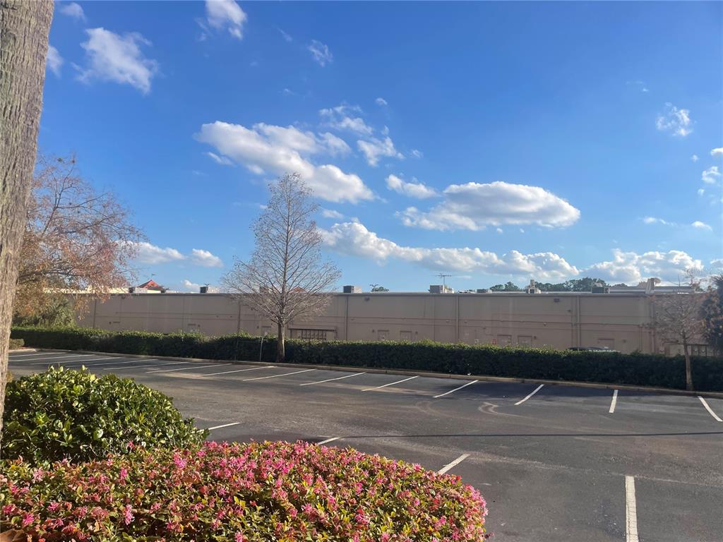 A parking lot sits in front of a long, beige commercial building under a blue sky — 8112 POINCIANA BOULEVARD UNIT 1509, ORLANDO, FL