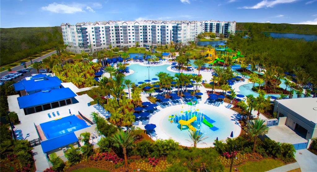 An aerial view of a resort pool area with water slides and a large apartment building — 14501 GROVE RESORT AVENUE UNIT 2214, WINTER GARDEN, FL