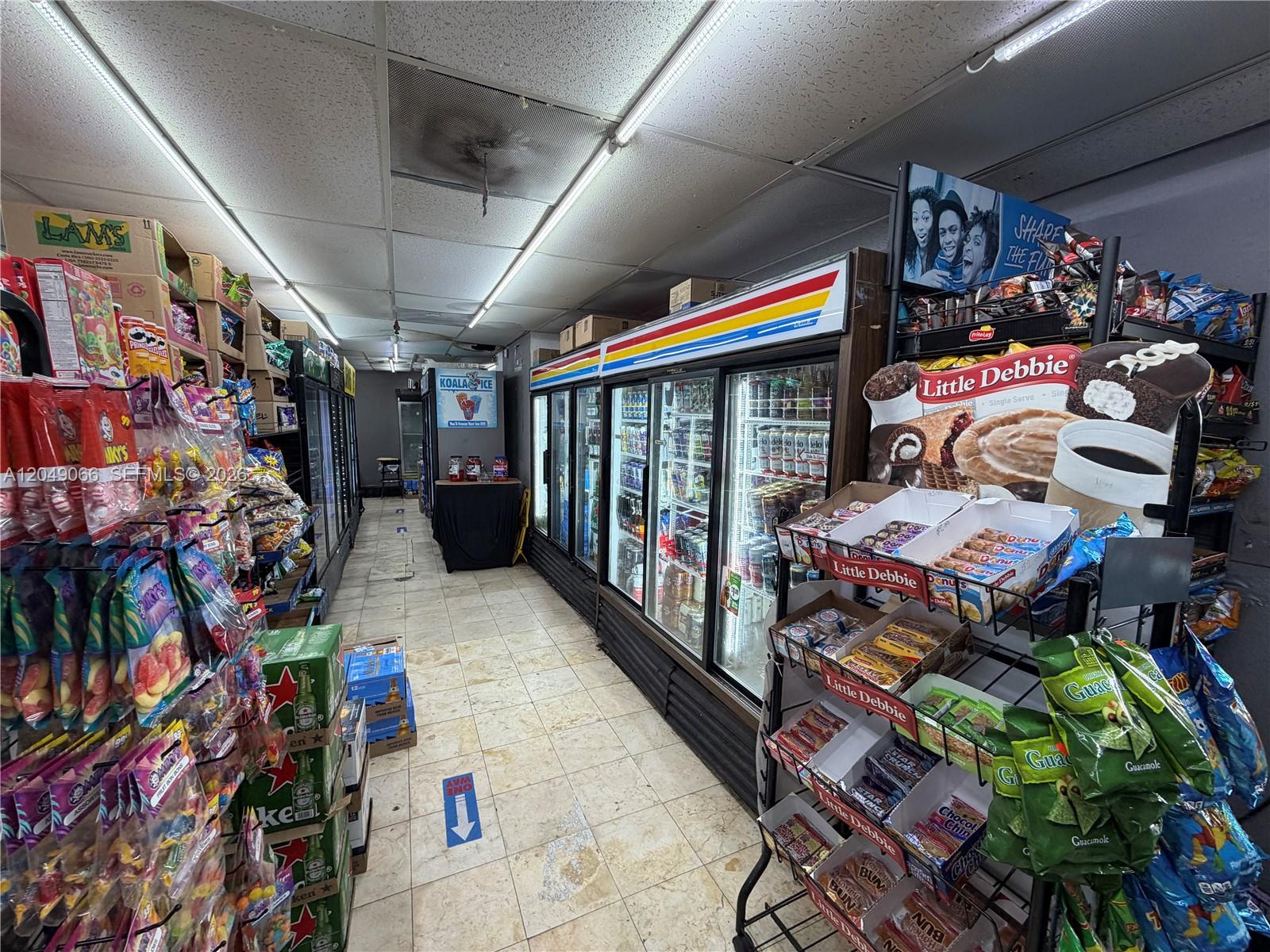A convenience store interior features rows of snack displays and glass-fronted beverage refrigerators — 4980 NW 22nd Ave, Miami FL 33142, MIAMI, FL